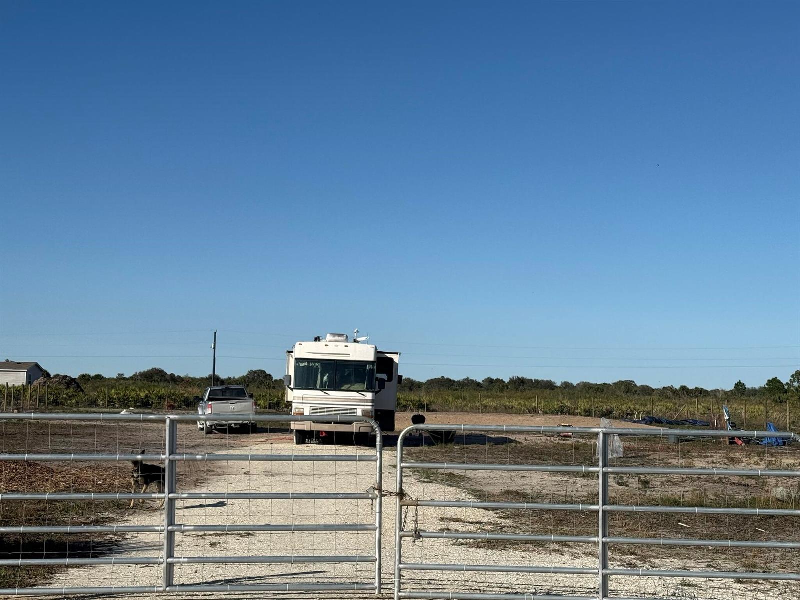 A motorhome and a pickup truck are parked on a gravel lot behind a gate — 21377 NW 276th Street, Okeechobee FL 34972, OKEECHOBEE, FL