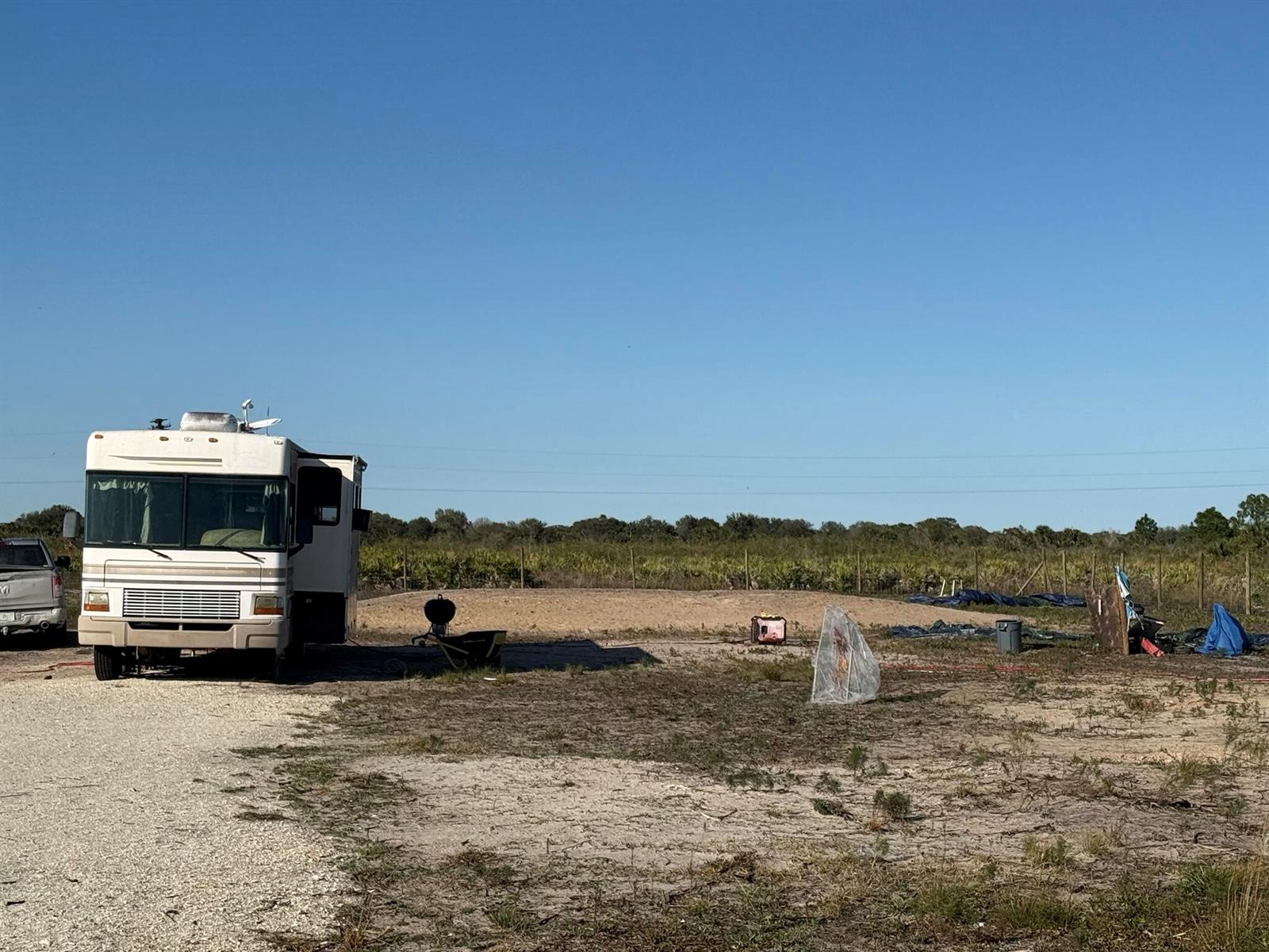 A white recreational vehicle is parked on a gravel lot next to a dirt mound — 21377 NW 276th Street, Okeechobee FL 34972, OKEECHOBEE, FL