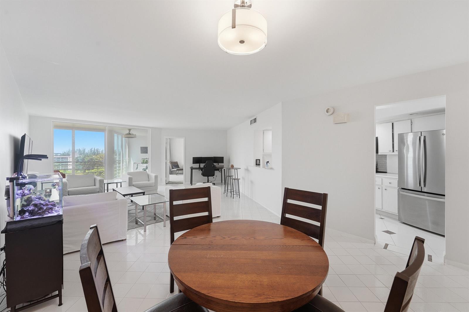 A dining area with a round wooden table overlooks a living room and a kitchen — 2681 S Course Drive # 808, Pompano Beach FL 33069, POMPANO BEACH, FL