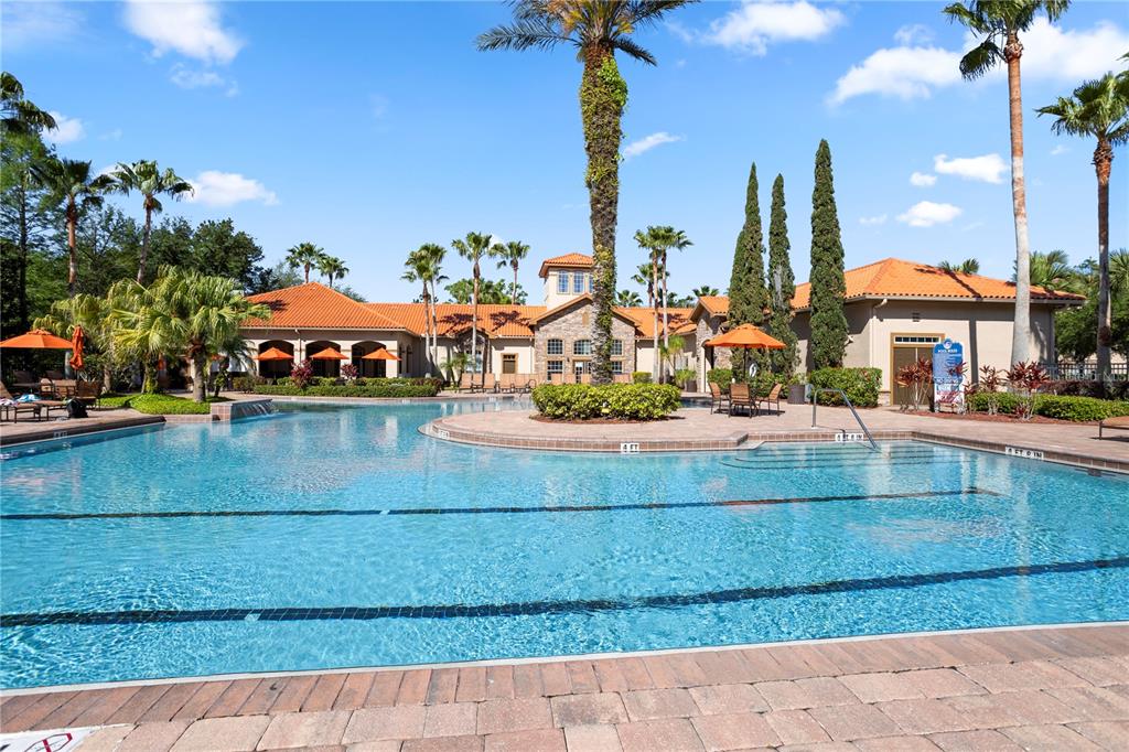 A large swimming pool sits in front of a clubhouse with a terracotta tile roof — 1370 TUSCAN TERRACE UNIT 2308, DAVENPORT, FL