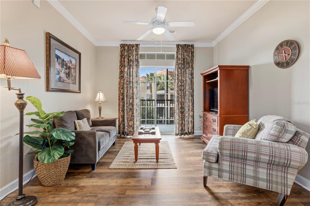 A living room features wood-look flooring, a ceiling fan, a sofa, an armchair, and balcony access — 1370 TUSCAN TERRACE UNIT 2308, DAVENPORT, FL