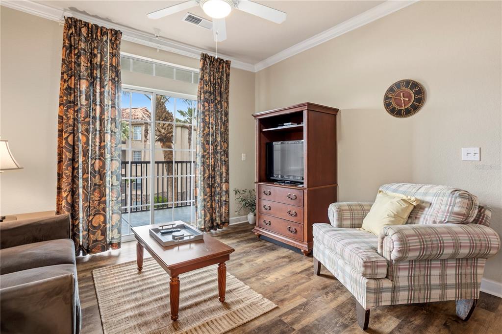 A living room features a plaid armchair, a wooden media console, and a sliding glass door — 1370 TUSCAN TERRACE UNIT 2308, DAVENPORT, FL