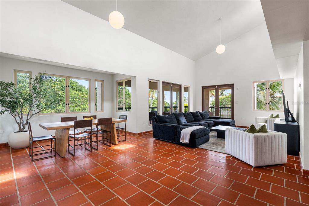 A spacious living and dining area features vaulted ceilings, terracotta tile floors, and large windows — 86 LAKESIDE VILLAS UNIT G2, VEGA ALTA, PR