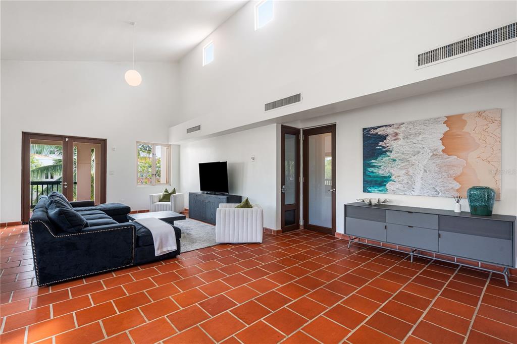 A living room with terracotta tile floors, a vaulted ceiling, and a large wall painting — 86 LAKESIDE VILLAS UNIT G2, VEGA ALTA, PR