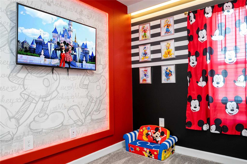 A Mickey Mouse-themed bedroom features a wall-mounted television, character wallpaper, framed wall art, and a small sofa — 4383 SCENE LANE, KISSIMMEE, FL