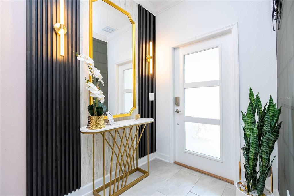 A modern entryway features a gold-framed mirror, a console table, and black vertical wall slats — 4383 SCENE LANE, KISSIMMEE, FL
