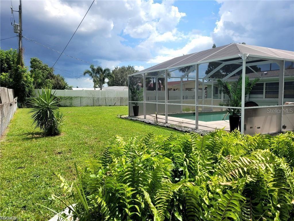 A backyard features a screened-in pool enclosure, a grassy lawn, and a white privacy fence — 2705 SE 17TH AVENUE, CAPE CORAL, FL