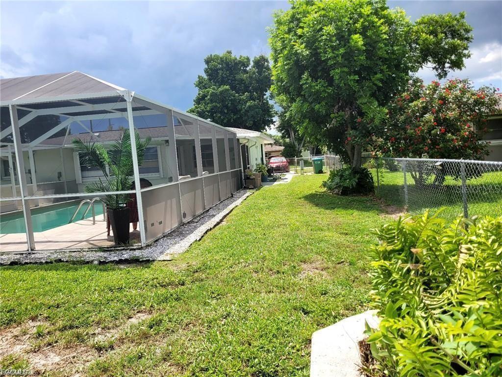 A backyard features a screened-in pool enclosure, a grassy lawn, and a chain-link fence — 2705 SE 17TH AVENUE, CAPE CORAL, FL