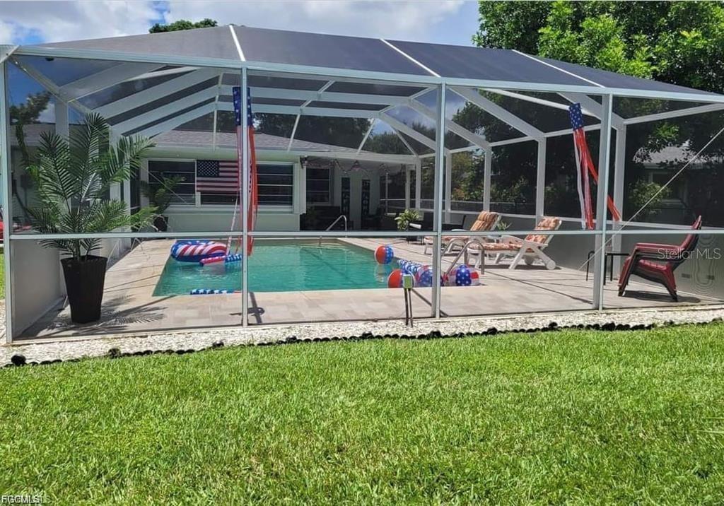 A swimming pool is enclosed by a screened lanai in a grassy backyard — 2705 SE 17TH AVENUE, CAPE CORAL, FL