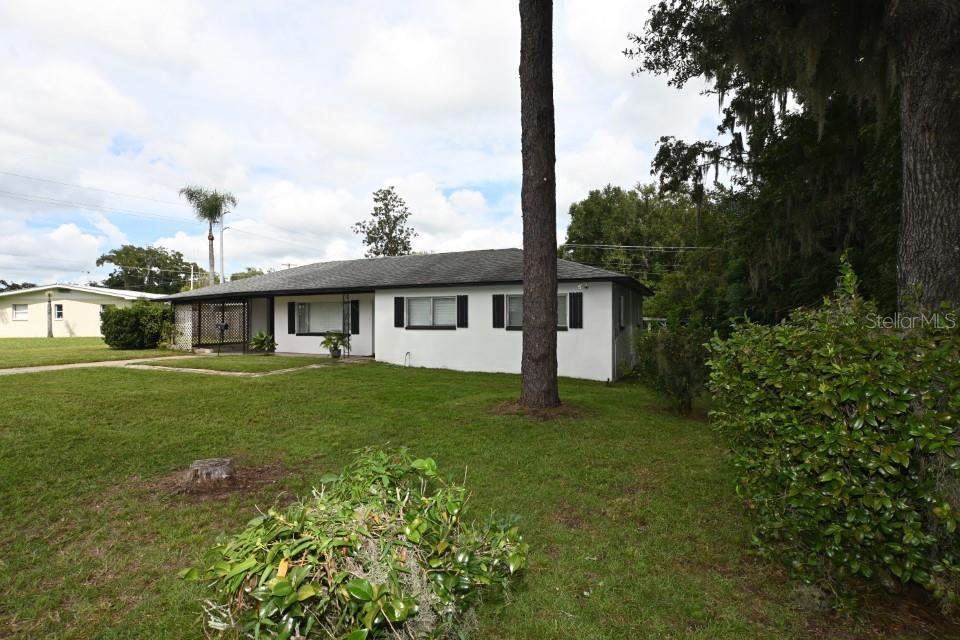 A white single-story house with a dark roof and black shutters sits on a lawn — 37017 MERIDIAN AVENUE, DADE CITY, FL