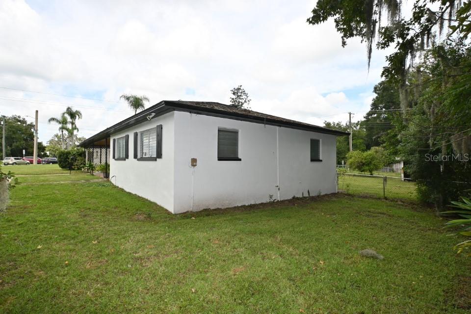 The exterior of a white, single-story house with a flat roof and a side porch — 37017 MERIDIAN AVENUE, DADE CITY, FL