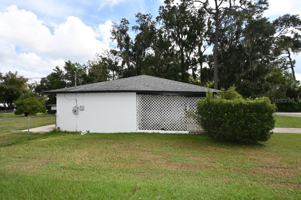 The exterior of a small house features a white wall, a lattice-enclosed porch, and a roof — 37017 MERIDIAN AVENUE, DADE CITY, FL