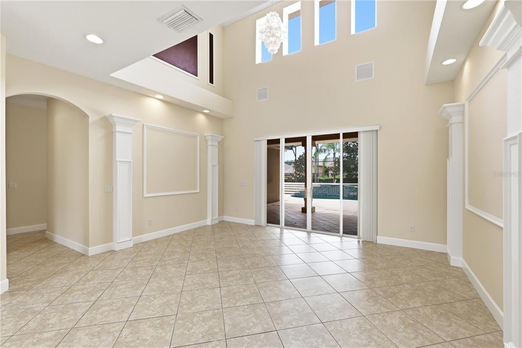 A spacious living room with high ceilings, tile flooring, and sliding glass doors to a pool — 3205 KING GEORGE DRIVE, ORLANDO, FL
