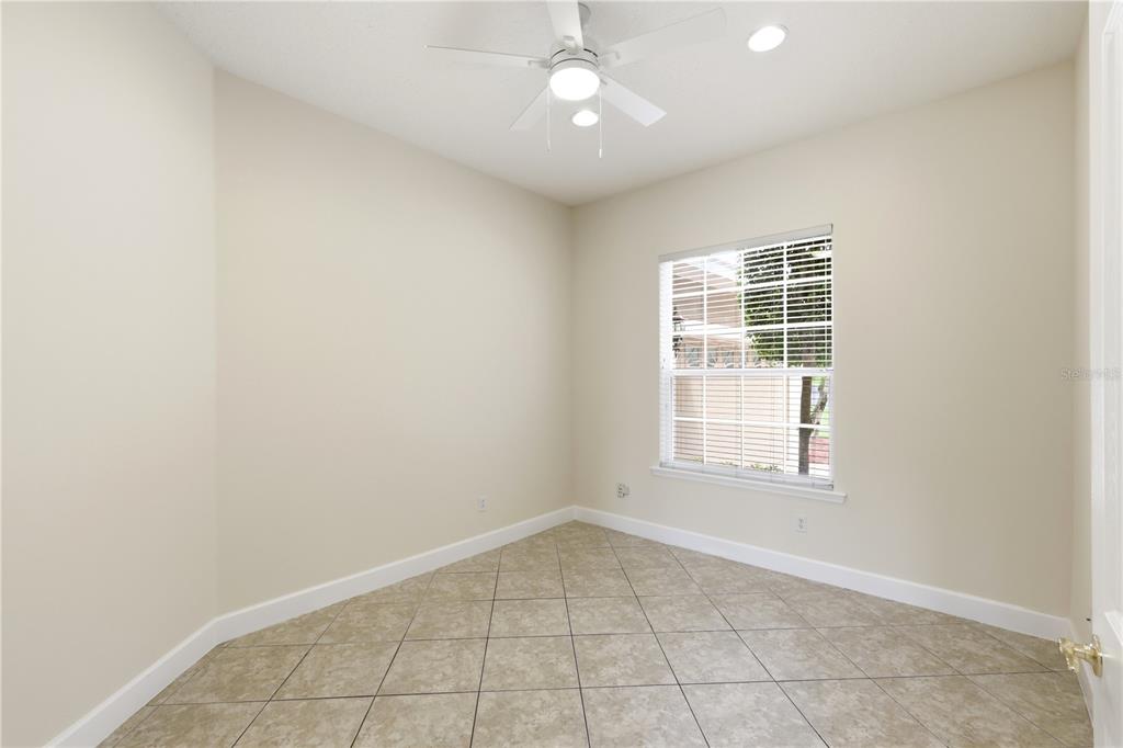 An empty room with beige walls, tile flooring, a ceiling fan, and a single window — 3205 KING GEORGE DRIVE, ORLANDO, FL