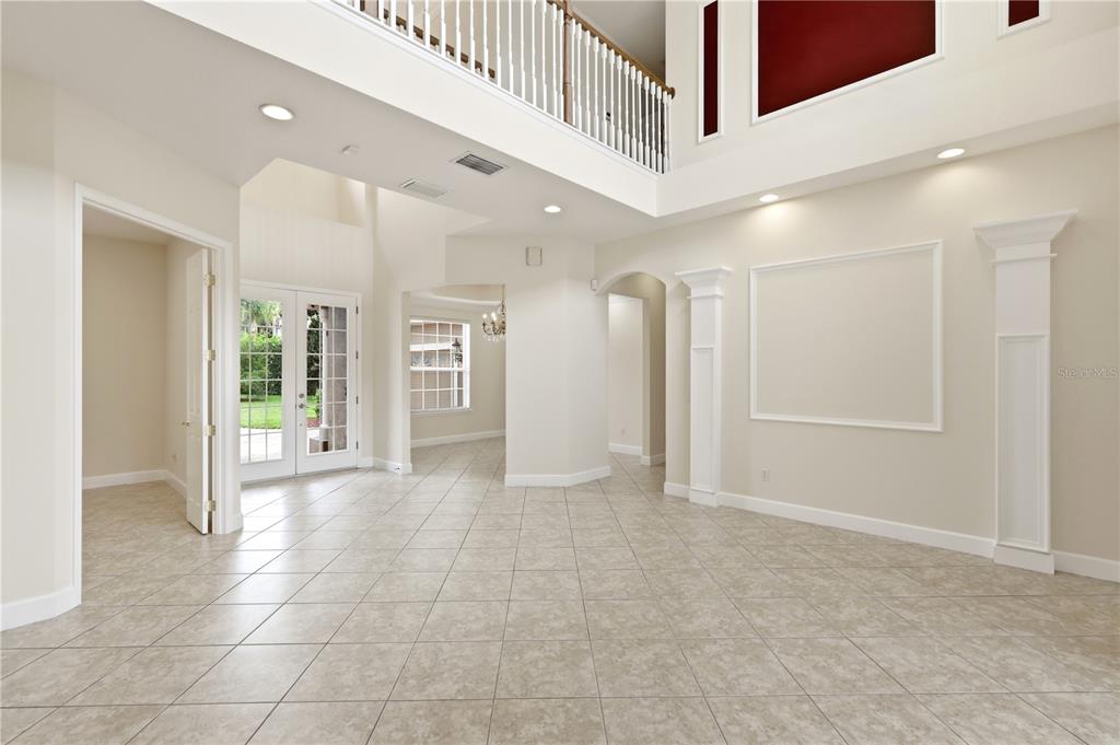 A bright, tiled foyer features a two-story ceiling, white columns, and a balcony railing — 3205 KING GEORGE DRIVE, ORLANDO, FL