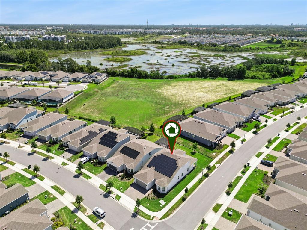 An aerial view of a suburban house with solar panels and a nearby pond — 13361 SUNNY RETREAT LANE, WINTER GARDEN, FL