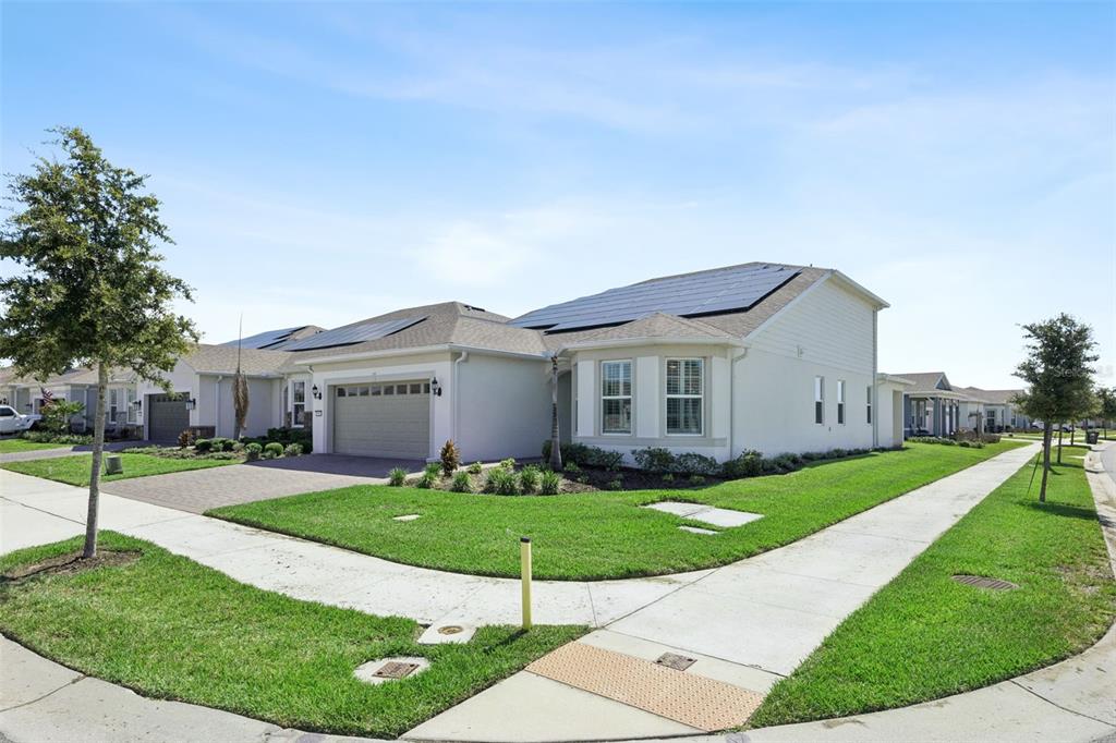 A single-story suburban house with a two-car garage and solar panels on the roof — 13361 SUNNY RETREAT LANE, WINTER GARDEN, FL