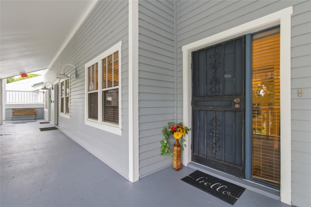 A gray-sided building exterior features a covered porch, a dark metal door, and large windows — 2599 DOLLY BAY DRIVE UNIT 306, PALM HARBOR, FL