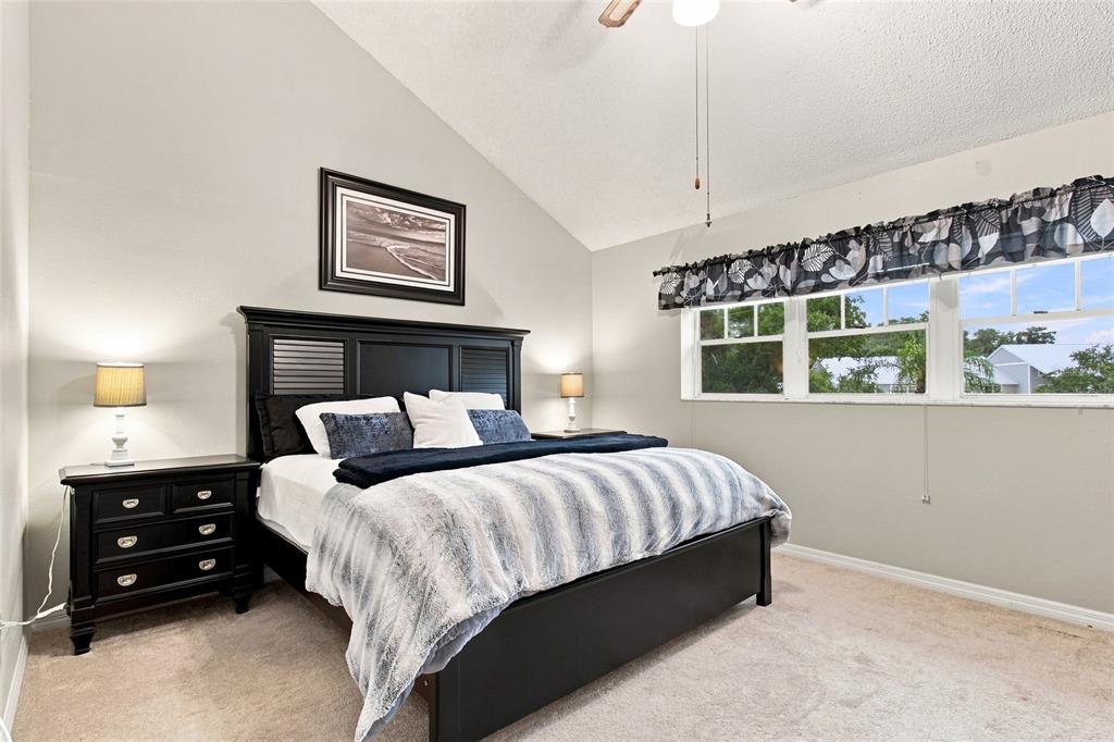 A bedroom features a black bed frame, matching nightstands, and a vaulted ceiling — 2599 DOLLY BAY DRIVE UNIT 306, PALM HARBOR, FL