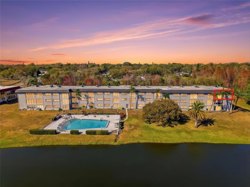 An aerial view of a multi-story apartment building with a swimming pool and a lake — 1303 S HERCULES AVENUE UNIT 25, CLEARWATER, FL