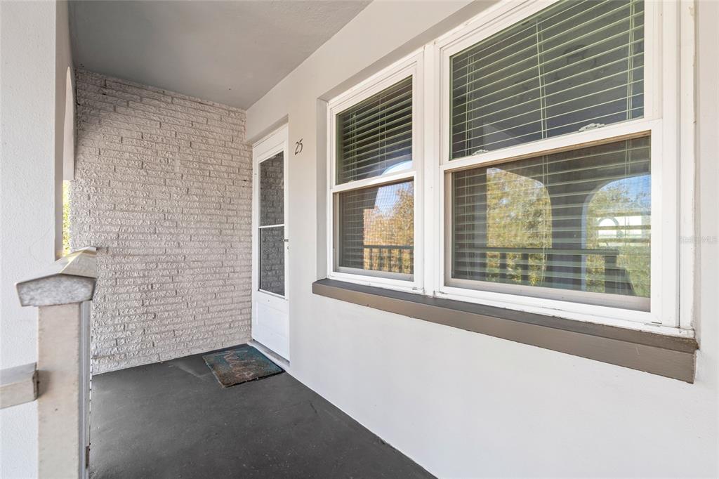 A covered porch features a white brick wall, a front door, and two large windows — 1303 S HERCULES AVENUE UNIT 25, CLEARWATER, FL