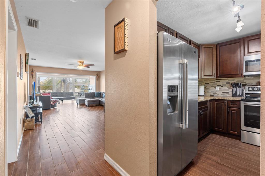 A view from a kitchen with dark cabinets toward a living room with wood flooring — 1303 S HERCULES AVENUE UNIT 25, CLEARWATER, FL