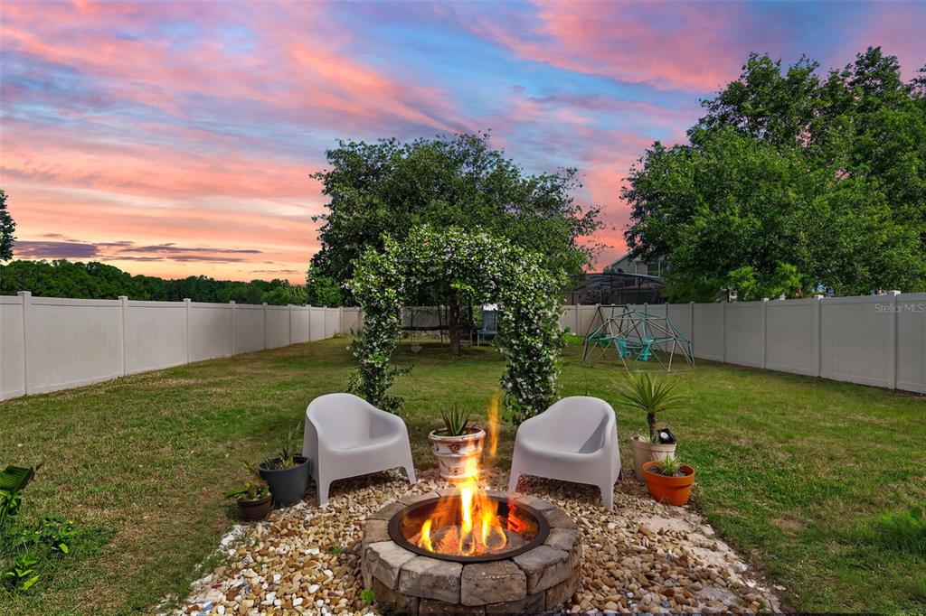 A backyard features a stone fire pit, two white chairs, and a floral archway — 34040 ALAMEDA DRIVE, SORRENTO, FL