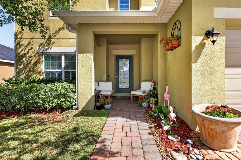 A paved walkway leads to a covered front porch with two chairs and a door — 34040 ALAMEDA DRIVE, SORRENTO, FL