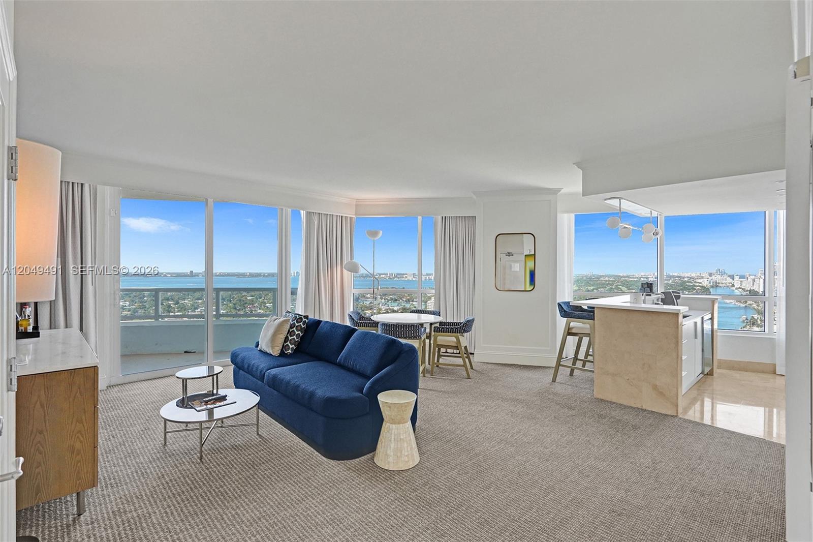 A living room with a blue sofa, dining area, and kitchen island overlooking the ocean — 4401 Collins Ave # 2915, Miami Beach FL 33140, MIAMI BEACH, FL