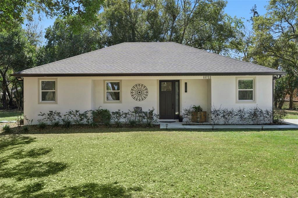 A single-story house with white stucco walls, a dark roof, and a front entryway — 11722 LAKE MINNEOLA SHORES, MINNEOLA, FL