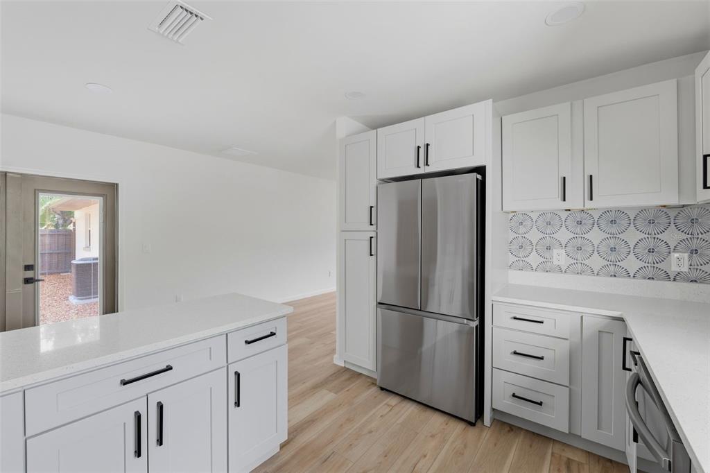 A modern kitchen features white cabinetry, stainless steel appliances, and a patterned tile backsplash — 3030 5TH STREET N, ST PETERSBURG, FL