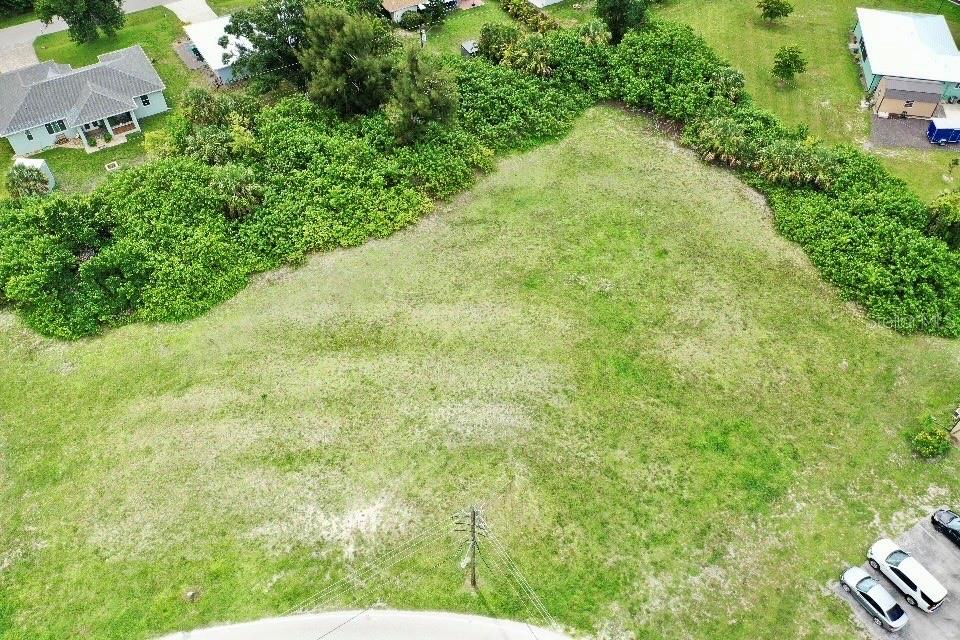 An aerial view shows a vacant, grassy residential lot bordered by trees and nearby houses — 2633 MAGDALINA DRIVE, PUNTA GORDA, FL