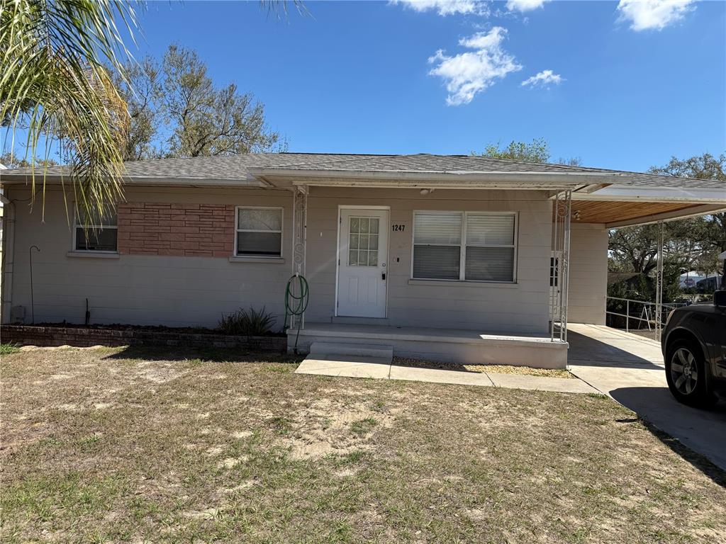 A single-story house with a beige exterior, a front porch, and an attached carport — 1247 LAKEVIEW DRIVE, CLERMONT, FL