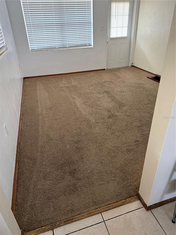 An empty room with brown carpet, white walls, a window with blinds, and a door — 1247 LAKEVIEW DRIVE, CLERMONT, FL