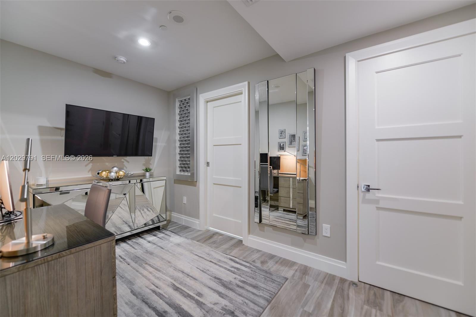 A home office features a mirrored console, a wall-mounted television, and a large wall mirror — 801 S Miami Ave # 3706, Miami FL 33130, MIAMI, FL