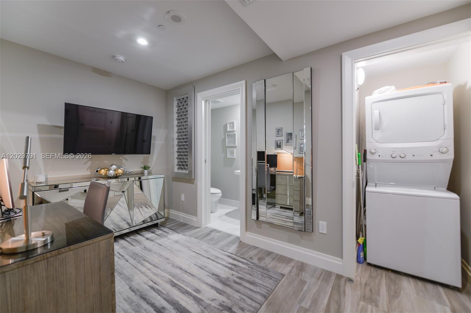 A home office features a desk, mirrored console, wall-mounted television, bathroom access, and a laundry closet — 801 S Miami Ave # 3706, Miami FL 33130, MIAMI, FL