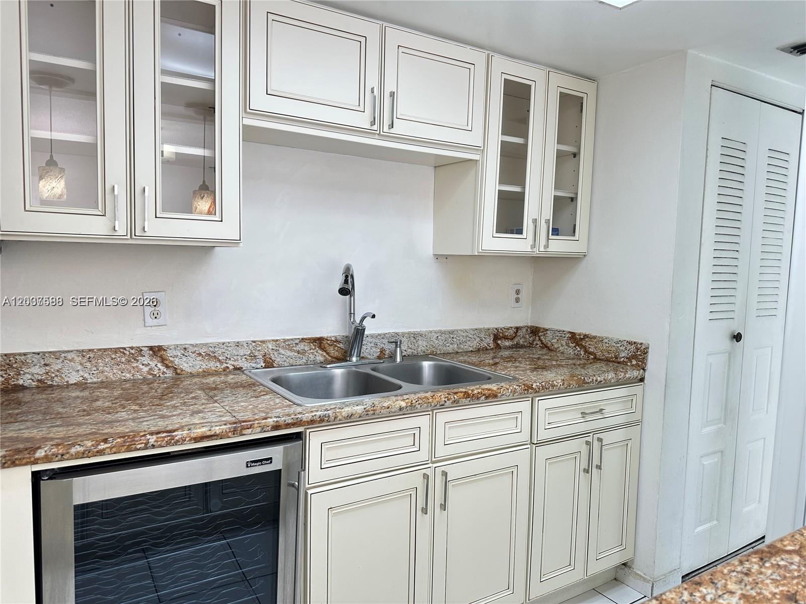 A kitchen features off-white cabinets, a granite countertop, a double sink, and a wine cooler — 802 NW 87th Ave # 315, Miami FL 33172, MIAMI, FL