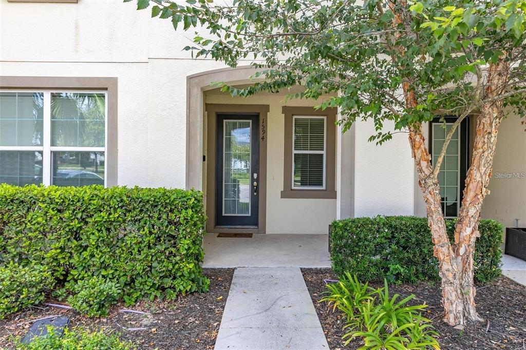A concrete walkway leads to the front entrance of a two-story home with landscaping — 1594 CAREY PALM CIRCLE, KISSIMMEE, FL