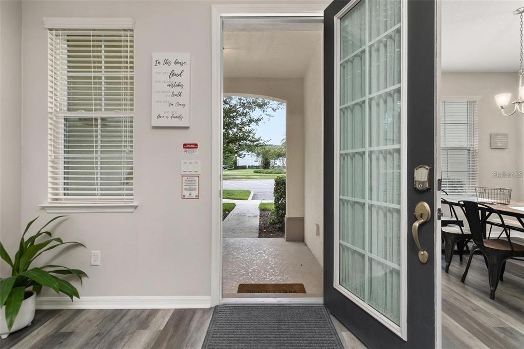 An open front door reveals a view of a sidewalk and neighborhood from an entryway — 1594 CAREY PALM CIRCLE, KISSIMMEE, FL