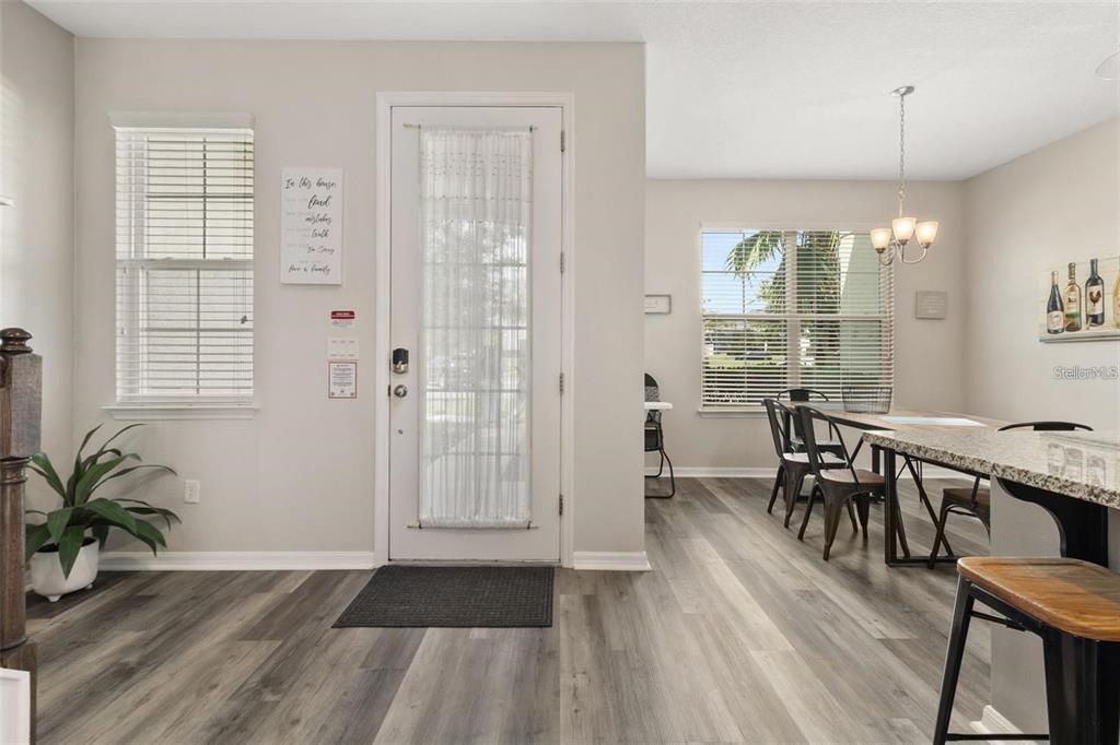 A dining area and entryway feature light gray walls, wood-look flooring, and a glass-paneled door — 1594 CAREY PALM CIRCLE, KISSIMMEE, FL