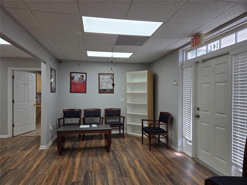 A waiting room features wood-look flooring, rows of chairs, a coffee table, and an exit door — 141 N OAKWOOD AVENUE, BRANDON, FL