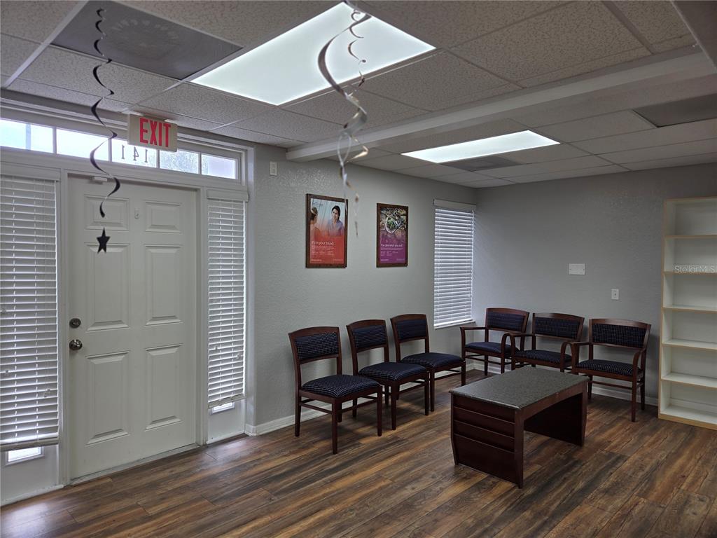 A room with wood-look plank flooring, a central support column, and a small seating area — 141 N OAKWOOD AVENUE, BRANDON, FL