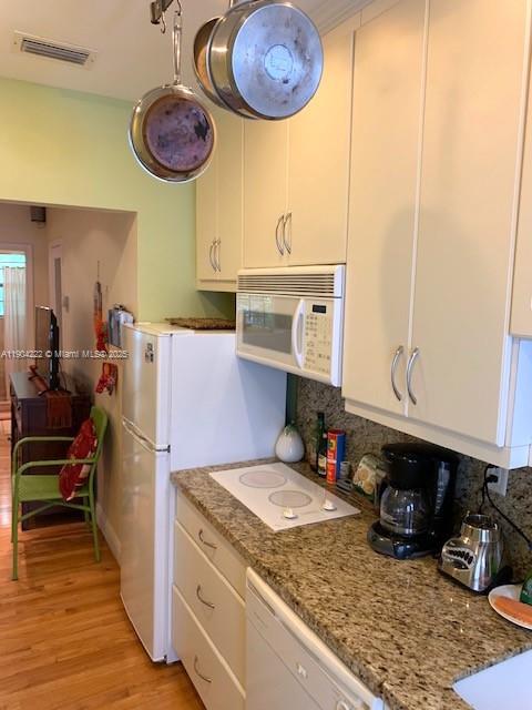 A kitchen features light-colored cabinets, granite countertops, a white refrigerator, and hanging cookware — 744 Lenox Ave # 3, Miami Beach FL 33139, MIAMI BEACH, FL