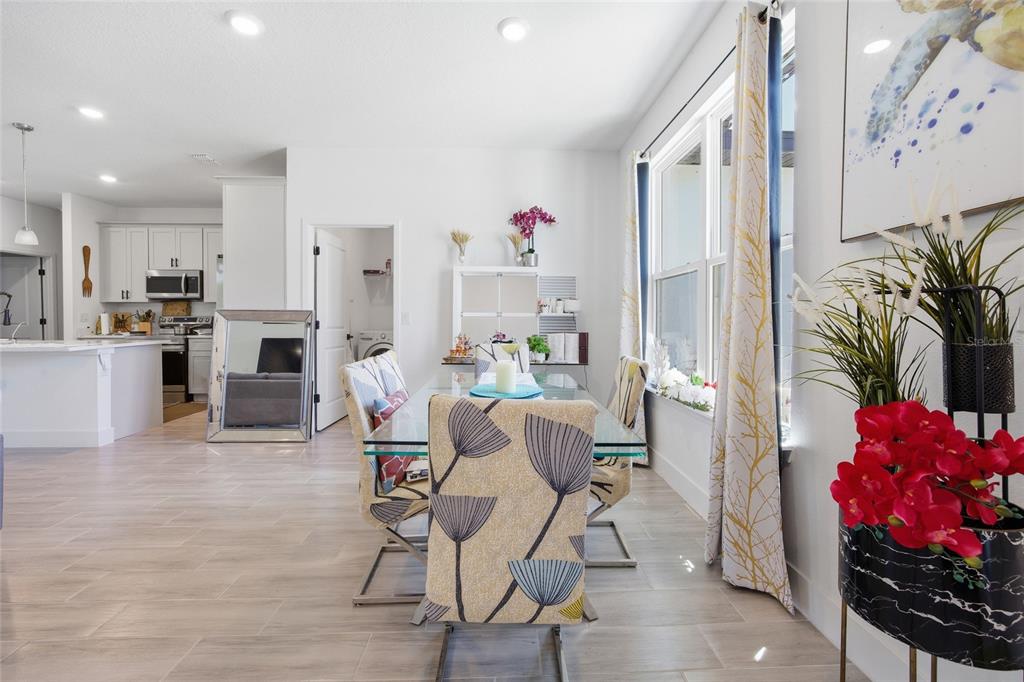 A dining area with a glass table, patterned chairs, and a view into the kitchen — 4411 SW 132ND PLACE, OCALA, FL