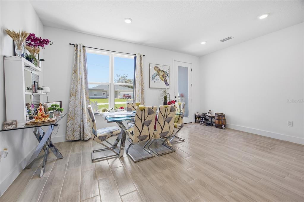 A dining room features a glass table, patterned chairs, tile flooring, and a glass door — 4411 SW 132ND PLACE, OCALA, FL