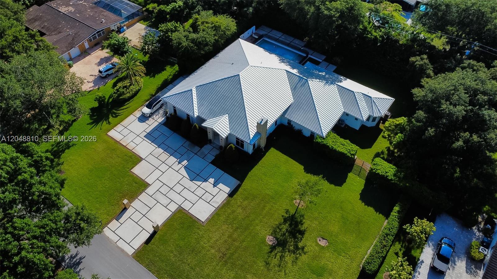 An aerial view shows a house with a metal roof, a pool, and a paved driveway — 9805 sw 90th ave, Kendall FL 33176, KENDALL, FL