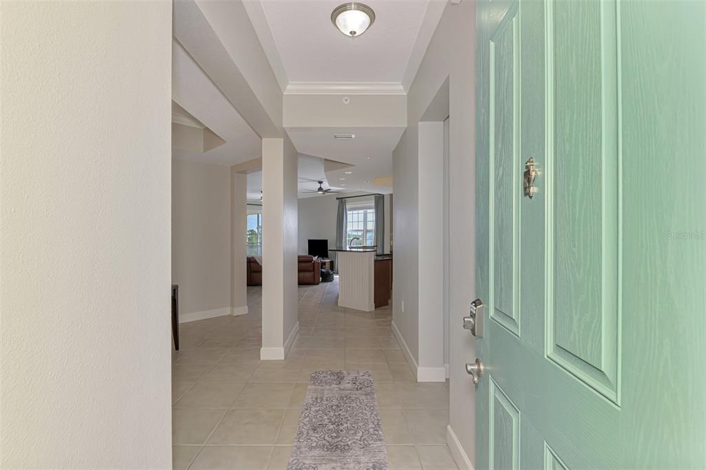 A view from a light green front door into a tiled foyer and open living area — 8571 AMBERJACK CIRCLE UNIT 204, ENGLEWOOD, FL