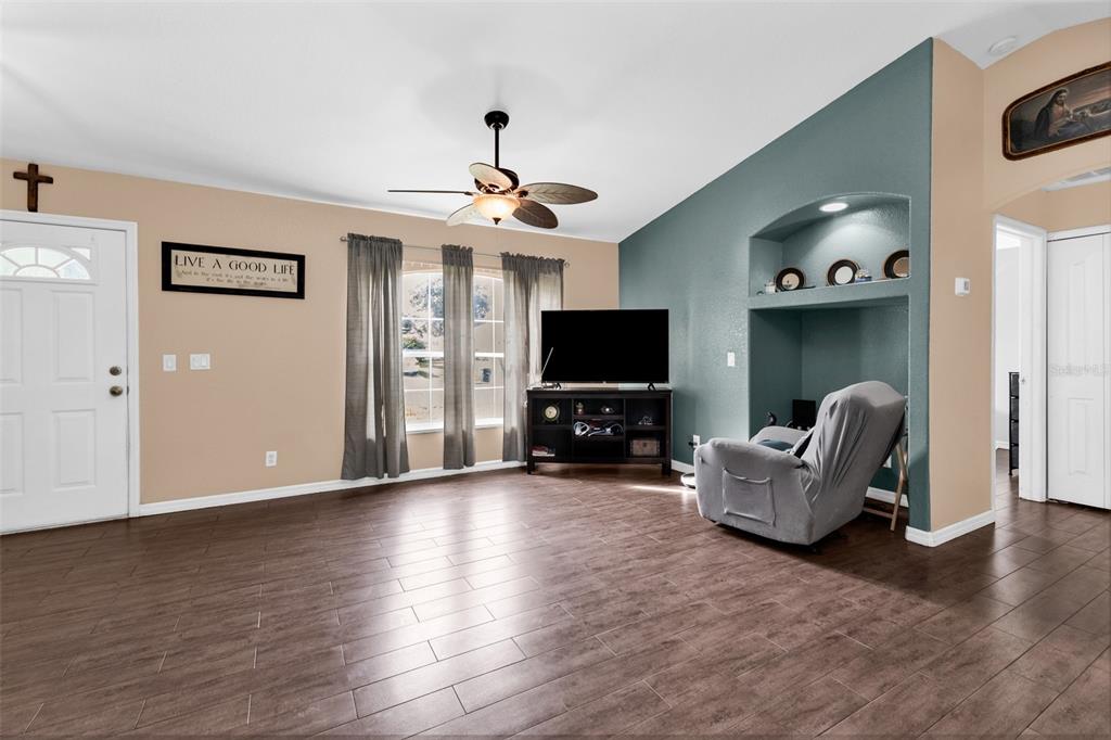 A living room features wood-look tile flooring, a ceiling fan, and a blue accent wall — 3237 CLEARFIELD STREET, NORTH PORT, FL