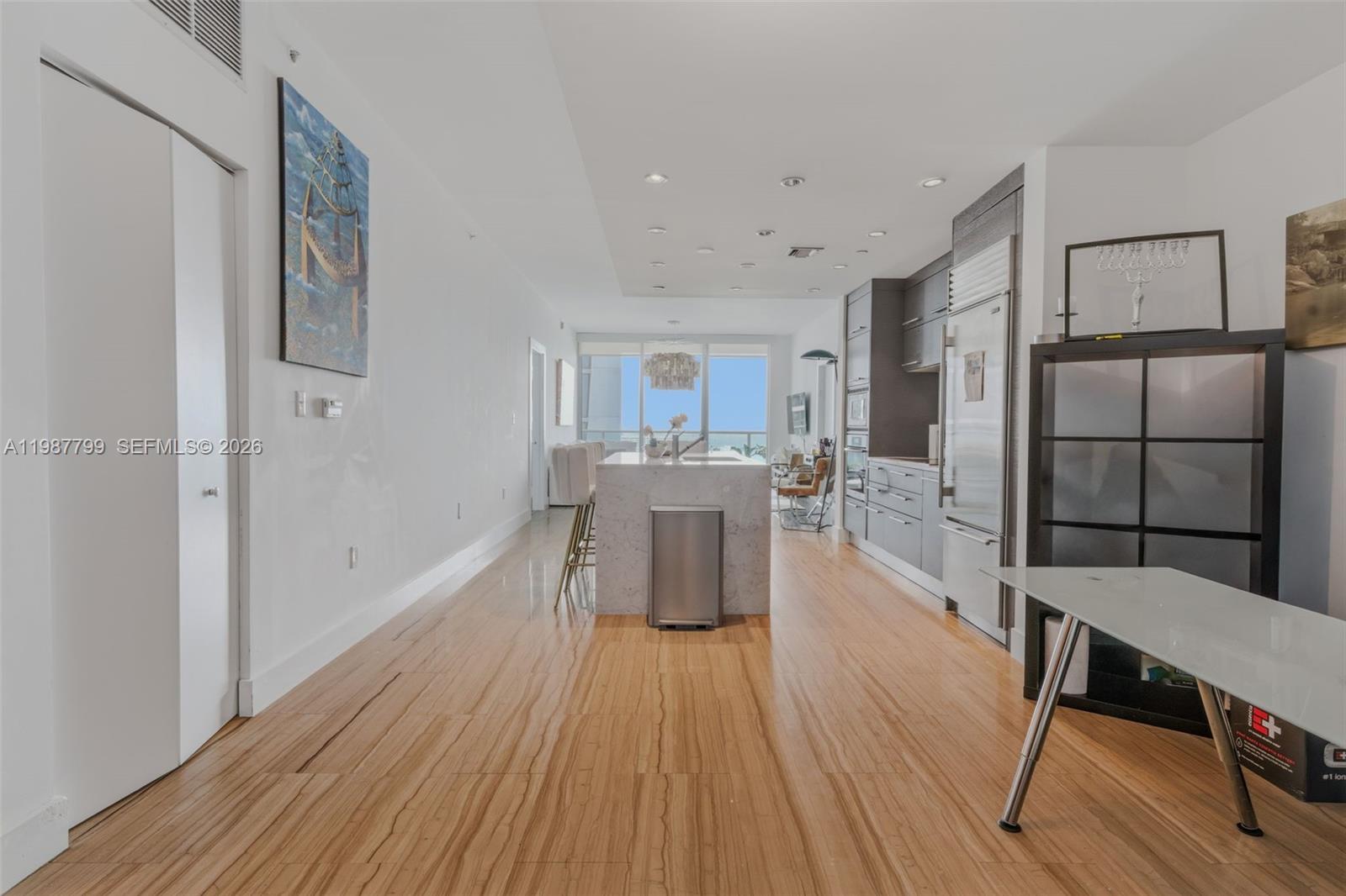 A modern kitchen features a marble island, dark cabinetry, and light wood flooring — 900 Biscayne Blvd # 4308, Miami FL 33132, MIAMI, FL