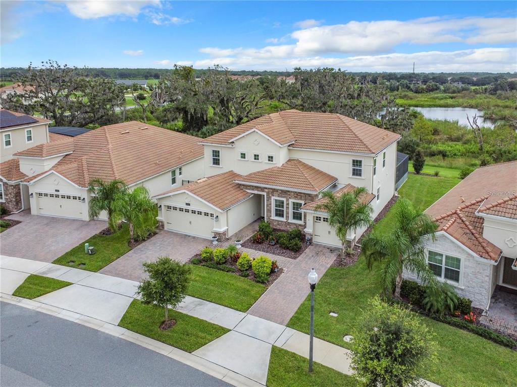 An aerial view shows a two-story suburban house with a tiled roof and paved driveway — 8886 FALLEN OAK DRIVE, DAVENPORT, FL